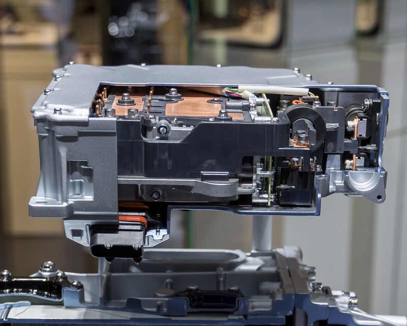 The future of electric vehicle power: This Audi electric motor control unit showcases the sophisticated power electronics that convert battery DC into AC motor drive signals. While today's systems rely on silicon carbide for high-efficiency switching, gallium oxide power semiconductors promise to handle higher voltages with dramatically reduced losses—if manufacturing costs can be brought under control. Source: Wikimedia Commons